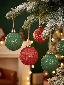Detailed view of red and green textured Christmas balls hanging on a pine tree