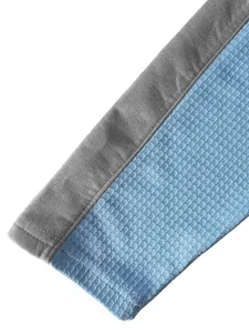 Vue détaillée du tissu en maille gaufrée bleue et du poignet de manche gris du sweat