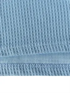Gros plan sur un tissu en maille gaufrée bleu clair avec coutures d'ourlet pour sweat.
