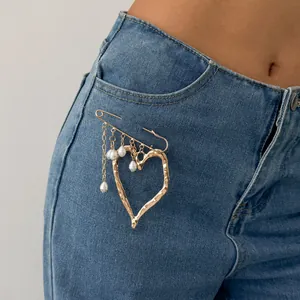 Exaggerated gold lava heart brooch with pearl tassels on denim, French style accessory.
