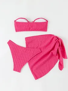 Detailed view of pink three-piece bikini set featuring a mesh wrap skirt