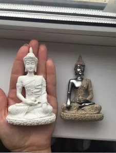 Close-up of miniature resin Buddha statues in hand showing size reference and intricate textures