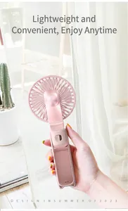 Close-up view of a hand holding a pink foldable handheld mini fan for personal cooling.