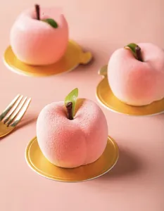 Close-up of realistic peach mousse cakes made with fruit-shaped silicone molds.