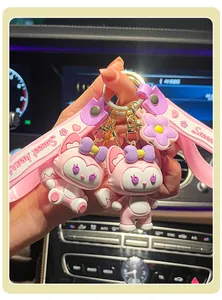 Close-up of cute pink fox cartoon keychain with purple bow and heart wrist strap.
