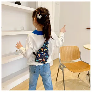 Child wearing navy cartoon dinosaur crossbody chest bag in a modern room setting