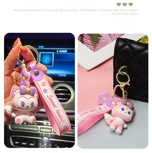 Close-up of a cute pink fox character keychain with a sweet heart strap on a black bag.