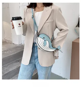 Lifestyle view of the cute blue and white whale-shaped crossbody bag worn with a blazer