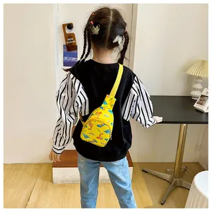Detail showing a child wearing a bright yellow cartoon dinosaur crossbody chest bag.