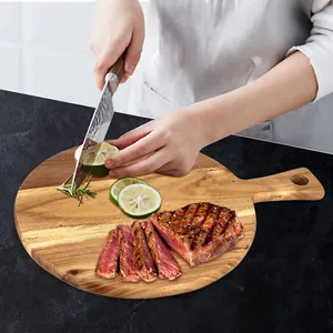 Handmade acacia wood cutting board used as a steak serving tray in a kitchen scene