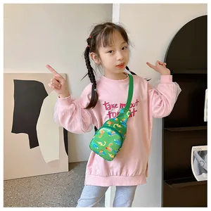 Close-up detail of children's green cartoon dinosaur crossbody chest bag on a girl