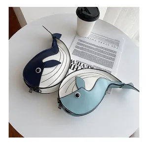 Close-up detail of two cute cartoon whale-shaped crossbody bags in blue and white colors