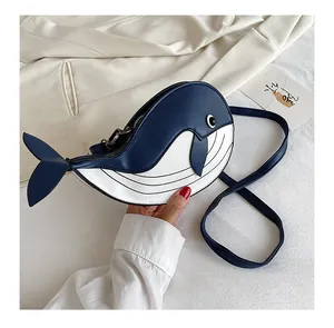 Detail view of a cute navy and white whale-shaped crossbody bag on beige fabric.