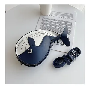 Top view of a cute blue and white whale-shaped crossbody bag on a white table