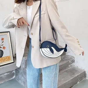 Close-up of a cute blue and white whale-shaped crossbody bag worn with a beige blazer