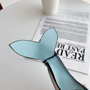Detail of a light blue whale-shaped crossbody bag with pebbled leather texture.