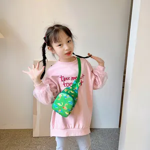 Cute green children's chest bag featuring a cartoon dinosaur print, worn by a young girl