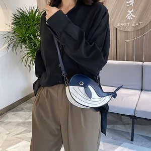 Cute blue and white whale-shaped crossbody bag shown on a model for scale and style.