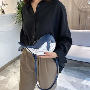Cute blue and white cartoon whale-shaped crossbody bag worn by a model in a cafe