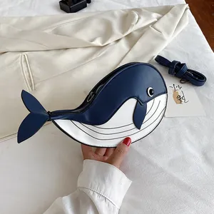 Close-up view of a unique blue and white whale-shaped cartoon crossbody bag on off-white fabric