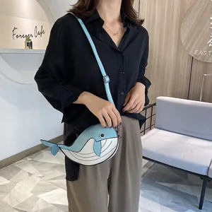 Model wearing a cute blue and white whale-shaped crossbody bag in a cafe setting