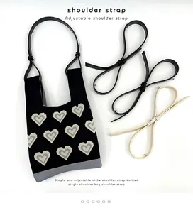 Detailed view of knitted heart bag with adjustable black and beige PU leather straps