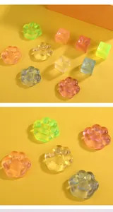 Macro view of transparent colorful cat paw and ice cube squishy toys on yellow surface