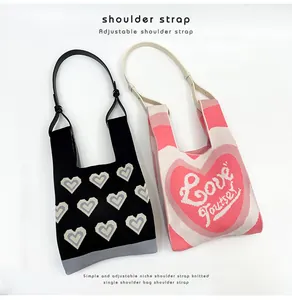 Detailed view of adjustable PU leather straps on heart-patterned knitted bags.