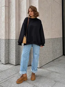 Full lifestyle shot of a woman in an oversized black fleece sweatshirt and light blue jeans.