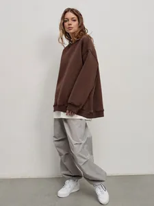 Woman wearing a brown oversized round neck sweatshirt paired with grey cargo pants