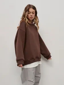 Woman in oversized brown crewneck sweatshirt featuring a street-style minimalist fit