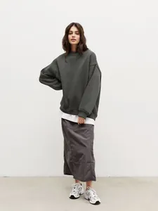Model wearing an oversized charcoal gray round neck sweatshirt in a minimalist studio