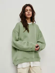 Detail of an oversized sage green crewneck fleece sweatshirt on a model