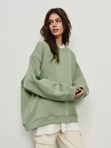 Close-up of oversized green crewneck sweatshirt with soft fleece texture and rib-knit cuffs