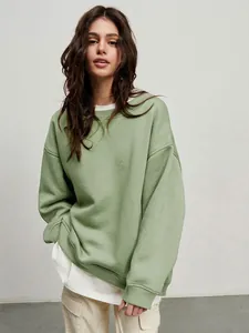 Detailed shot of an oversized sage green crewneck sweatshirt on a model in studio