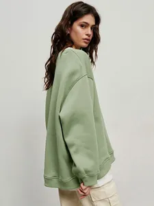 Detailed side view of a premium oversized sage green crewneck sweatshirt on a model