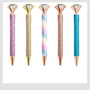 Close-up detail of glitter metal ballpoint pens featuring large crystal diamond tops in various colors.