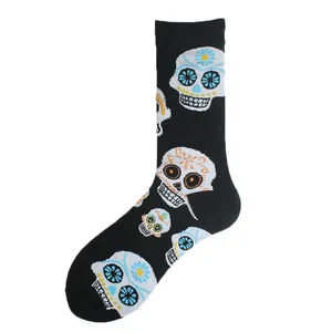 Close-up of black crew socks with vibrant Mexican sugar skull patterns on white backdrop.