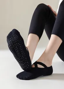Detail of black yoga socks with criss-cross straps and non-slip silicone grip dots sole.