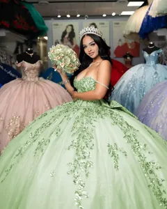 Détail d'une robe de bal Quinceañera vert sauge avec broderie florale à paillettes sur modèle
