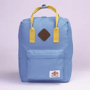 Mochila escolar minimalista azul y amarilla con etiqueta Dilash y detalle de parche marrón
