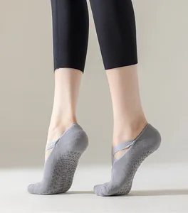 Detailed view of grey non-slip Pilates socks with cross straps shown on model feet