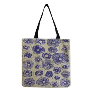 Close-up view of a beige canvas tote bag with artistic blue mushroom prints on it