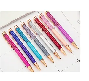 Detailed view of colorful metal ballpoint pens with floating glitter and gold accents