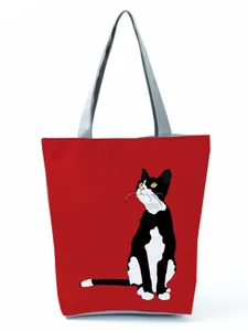 Vibrant red canvas tote bag featuring a cute sitting black and white cat graphic print