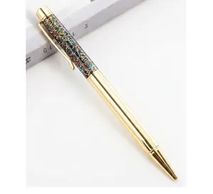 Macro view of a gold metal ballpoint pen featuring a colorful glitter-filled barrel.