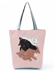 Close-up detail of a pink canvas tote bag featuring a cute stacked three-cat graphic print.