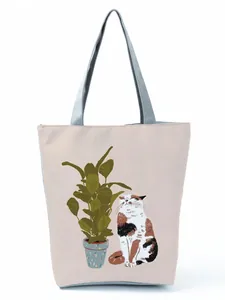 Adorable cat and potted plant graphic print on a stylish cream-colored tote bag detail.