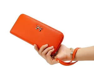 Primer plano de una cartera larga de cuero PU naranja con lazo metálico y correa de muñeca.