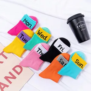Close-up view of seven pairs of colorful cotton socks with printed weekday names on cuffs